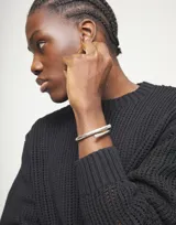 Pulsera rígida plateada con forma de espiral, fabricada en aleación de metales bañada en plata de ley.