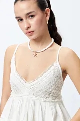 Top blanco con breteles finos y detalle de encaje en el escote.