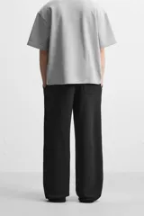 Pantalón jogger negro de corte ancho, confeccionado en tejido de algodón con interior de rizo. Cuenta con cintura elástica ajustable con cordón interior, bolsillos laterales y bolsillo trasero de parche.