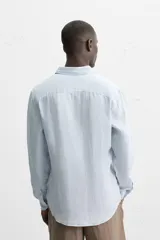 Camisa celeste de lino, de corte recto, manga larga y cuello clásico.