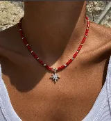 Collar corto de cuentas tubulares rojas alternadas con pequeñas cuentas plateadas. Dije colgante de estrella plateada con incrustaciones de circonitas.