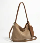 Bolso tipo hobo color marrón claro, con correa larga regulable y desmontable, asas cortas para llevar al hombro y un monedero externo. Confeccionada en cuero sintético.