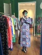 Vestido largo de crepe estampado con diseño geométrico en tonos azules, rojos y blancos. Tiene mangas largas acampanadas y cuello redondo.