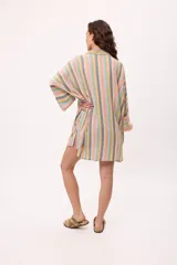 Vestido camisero a rayas verticales de colores pastel, con cuello camisero, cierre frontal con botones y mangas largas.