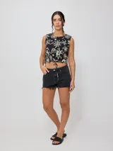 Top corto negro con estampado de flores y figuras geométricas en color crema, con breteles anchos y lazo ajustable en la cintura.