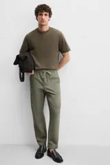 Pantalón de jogging color beige confeccionado en tejido de mezcla de algodón. Cuenta con cintura elástica ajustable con cordón, bolsillos frontales y traseros.