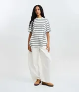 Remera oversized de algodón con cuello redondo, mangas cortas y estampado de rayas horizontales en tonos beige y marrón.