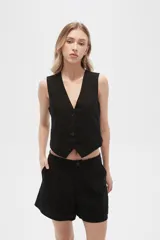 Chaleco negro sin mangas con cuello en V y cierre frontal con botones.