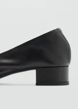 Zapato de cuero negro con tacón bloque y hebilla decorativa.