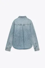 Camisa de denim celeste, de corte recto, con cuello solapa, manga larga, dos bolsillos frontales con solapa y cierre frontal con botones.