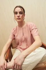 Blusa blanca de tela liviana con mangas cortas con volados y botón de nácar.