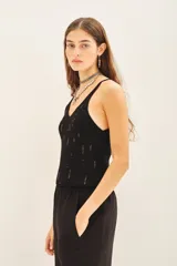 Musculosa negra de tejido rib con lentejuelas bordadas a tono, de calce al cuerpo y escote en V.