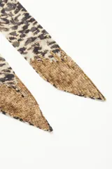 Pañuelo largo de poliéster con estampado animal print en tonos beige y negro.