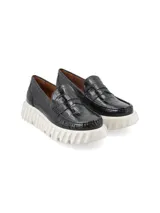 Mocasín de cuero negro con textura croco y plataforma blanca texturada.