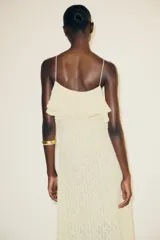 Vestido midi color crema confeccionado en encaje, con escote recto, tirantes finos, volantes y tachas.