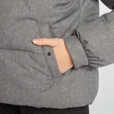 Campera puffer gris de franela con cuello de piel sintética negra, cierre frontal con cremallera dorada y bolsillos laterales.