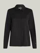 Camisa negra de viscosa con corte amplio, cuello inglés, tapeta de botones oculta, puños abotonados y logo metálico en la manga.