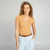 Camiseta color beige de corte ajustado, con cuello en V y tres botones decorativos.