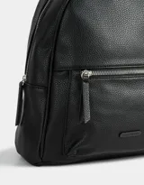Mochila negra de cuerina con bolsillo frontal con cierre, correas regulables, manija superior, cierre superior y tag de metal.