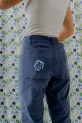 Pantalón de jean azul con bolsillos frontales y traseros. Presenta bordados de flores en los bolsillos traseros.