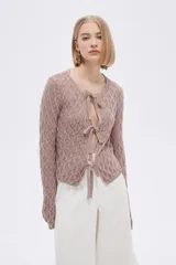 Saco de tejido de punto calado color marfil con escote en V y lazos para atar en el frente.