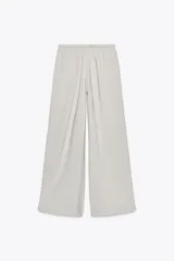 Pantalón palazzo color verde oliva de tejido fluido, tiro medio, cintura elástica ajustable con cordones y bolsillos laterales.