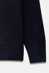 Jersey de punto azul marino confeccionado en 100% lana, de corte recto, con cuello redondo y mangas largas.