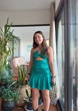 Vestido corto con estampado de rayas horizontales en tonos grises y negros. Diseño con escote halter que se ata al cuello, abertura central en el busto y falda corta con volado.