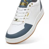 Zapatillas deportivas de cuero blanco con detalles en azul y suela de goma color marrón.