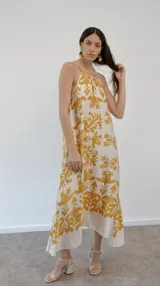 Vestido largo de seda estampada con flores amarillas sobre fondo blanco, corte halter.