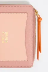 Monedero negro de piel con estructura rígida, logo metálico dorado, tirador de cordón y acabados metálicos dorados. Tarjetero interior, cierre con botón de presión e interior con logo grabado. Confeccionada en 100% poliéster reciclado y 100% poliuretano de producción responsable.