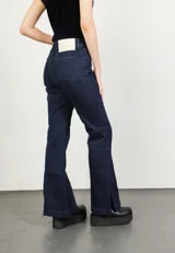 Pantalón de jean azul oscuro con corte acampanado y tajo en los laterales.