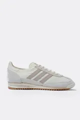 Championes Adidas SL 72 OG, color blanco hueso con detalles en gris topo, confeccionados en nylon y gamuza, con las tres tiras laterales en cuero sintético y suela de goma marrón.