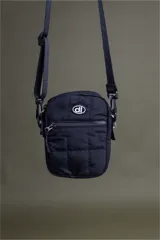 Bandolera negra acolchada con correa ajustable y logo circular blanco en el frente.