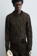 Sweater marrón oscuro de punto con estructura de trenzas, cuello redondo, manga larga y corte regular fit.