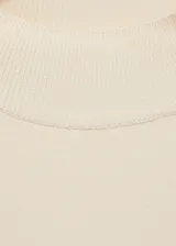 Sweater color crema de punto fino con cuello perkins y manga larga. Presenta detalle de botones metálicos en el hombro.