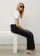 Pantalón de jean negro de corte wide leg, con tiro alto, cinco bolsillos, trabillas y bajo deshilachado.