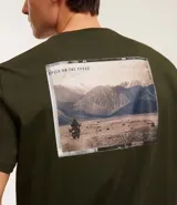 Remera verde militar de algodón, corte clásico, con cuello redondo y mangas cortas. Estampado frontal con texto en color claro.