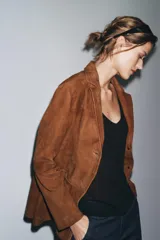 Blazer marrón de ante con cuello de solapa de muescas, manga larga, bolsillos de parche delanteros y cierre frontal con botones.