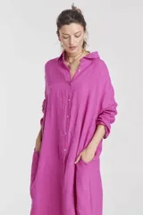 Vestido camisero largo color fucsia, de lino, con cuello camisero, mangas largas, cierre frontal con botones, bolsillos laterales y aberturas laterales en el ruedo.
