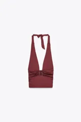 Top negro de cuello halter ajustable con lazadas, espalda descubierta, detalle de aplicación metálica en el delantero y drapeado lateral.