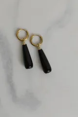 Par de aros dorados con cierre de gancho y dije colgante en forma de lágrima de piedra negra.