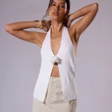 Top blanco con escote halter y detalle de flor en el centro.