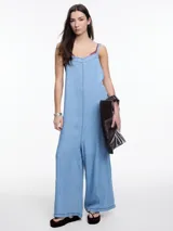 Enterito de denim suave de lyocell, color celeste, con escote recto, breteles regulables con lazo en la espalda, bolsillos traseros y costuras a contratono.