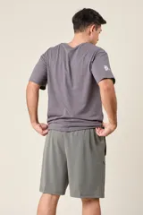Bermuda deportiva de nylon color gris, de corte suelto, con cintura elástica y cordón de ajuste. Cuenta con detalles de líneas en los costados y bolsillos con cierre.