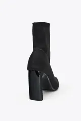Botín negro de tejido elástico con puntera fina y tacón cuadrado.