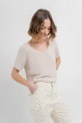 Remera tejida de manga corta, color gris claro, con escote en V y calce relajado. Presenta terminaciones acanaladas en mangas y ruedo.