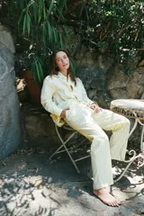 Pantalón tipo pijamero con tiro alto y cintura elástica, confeccionado en hilatura con algodón y lino. Presenta un estampado a rayas verticales en color amarillo y blanco, y detalle de botones decorativos en el delantero.