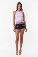Microshort negro de gabardina con estampado abstracto, tiro bajo y corte ajustado. Presenta costuras rojas, cierre metálico y presillas largas con detalle de avío en recorte de canesú.