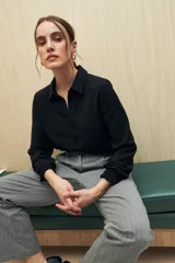 Camisa blanca de manga larga con textura sutil y caída fluida. Presenta cuello clásico, botones forrados a tono y puños con terminación fruncida.